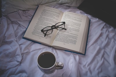 一杯咖啡在打开书的眼镜
